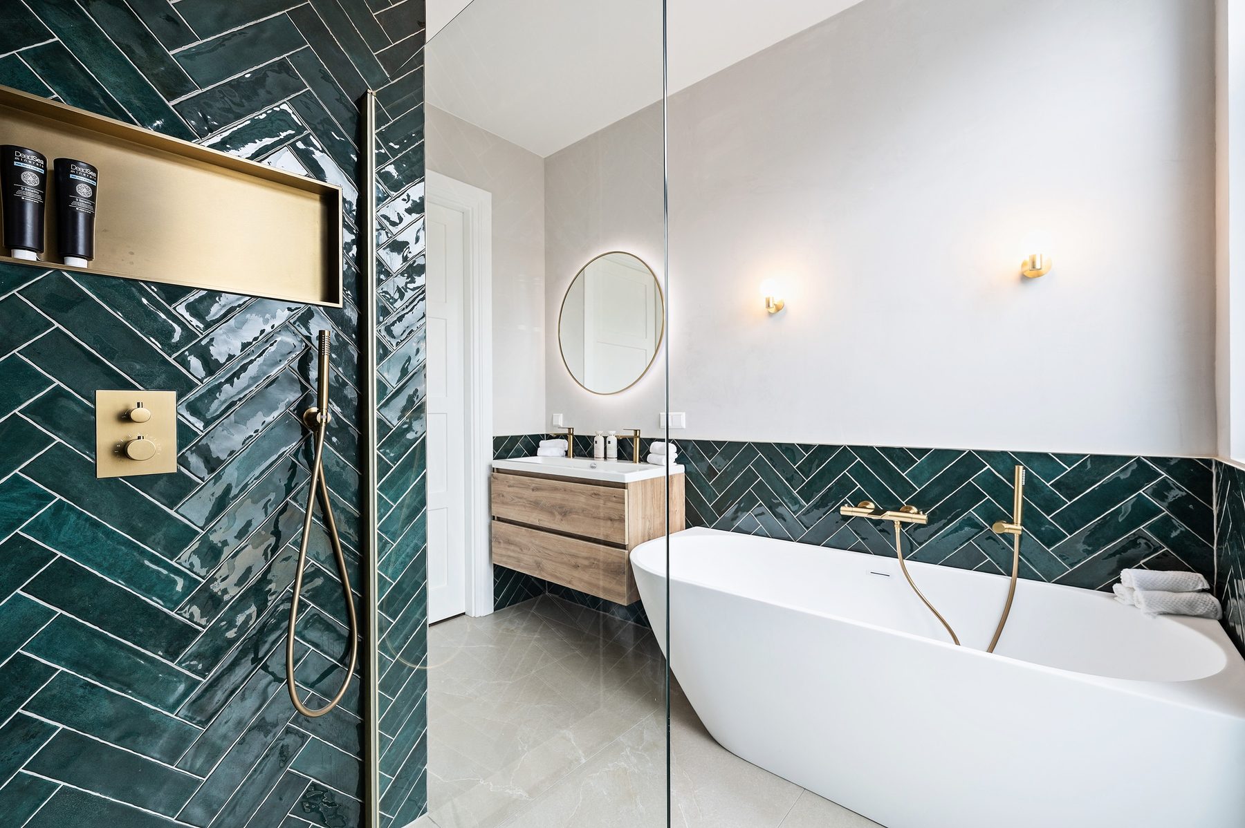 Badkamer met diepgroen visgraattegelwerk en vrijstaand bad